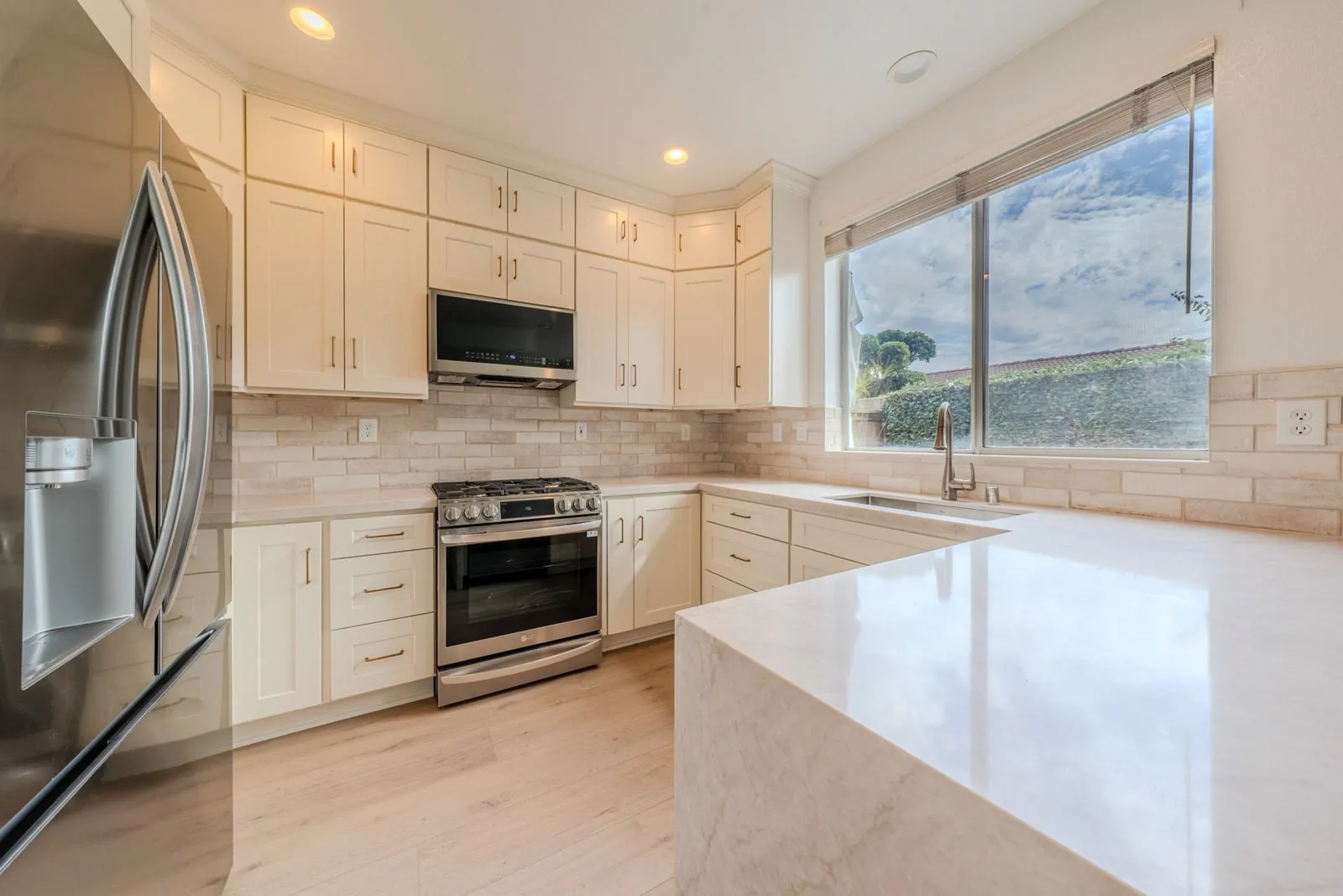 Cream shaker kitchen with waterfall quartz countertop and mountain-view window