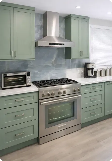 Sage green shaker kitchen cabinets with stainless range hood and gray tile backsplash
