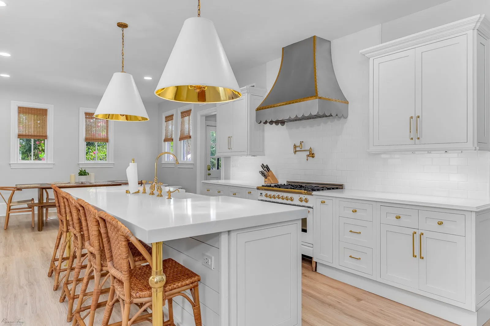 Finished white inset shaker kitchen with quartz island, gold pendant lights, and wood counter stools